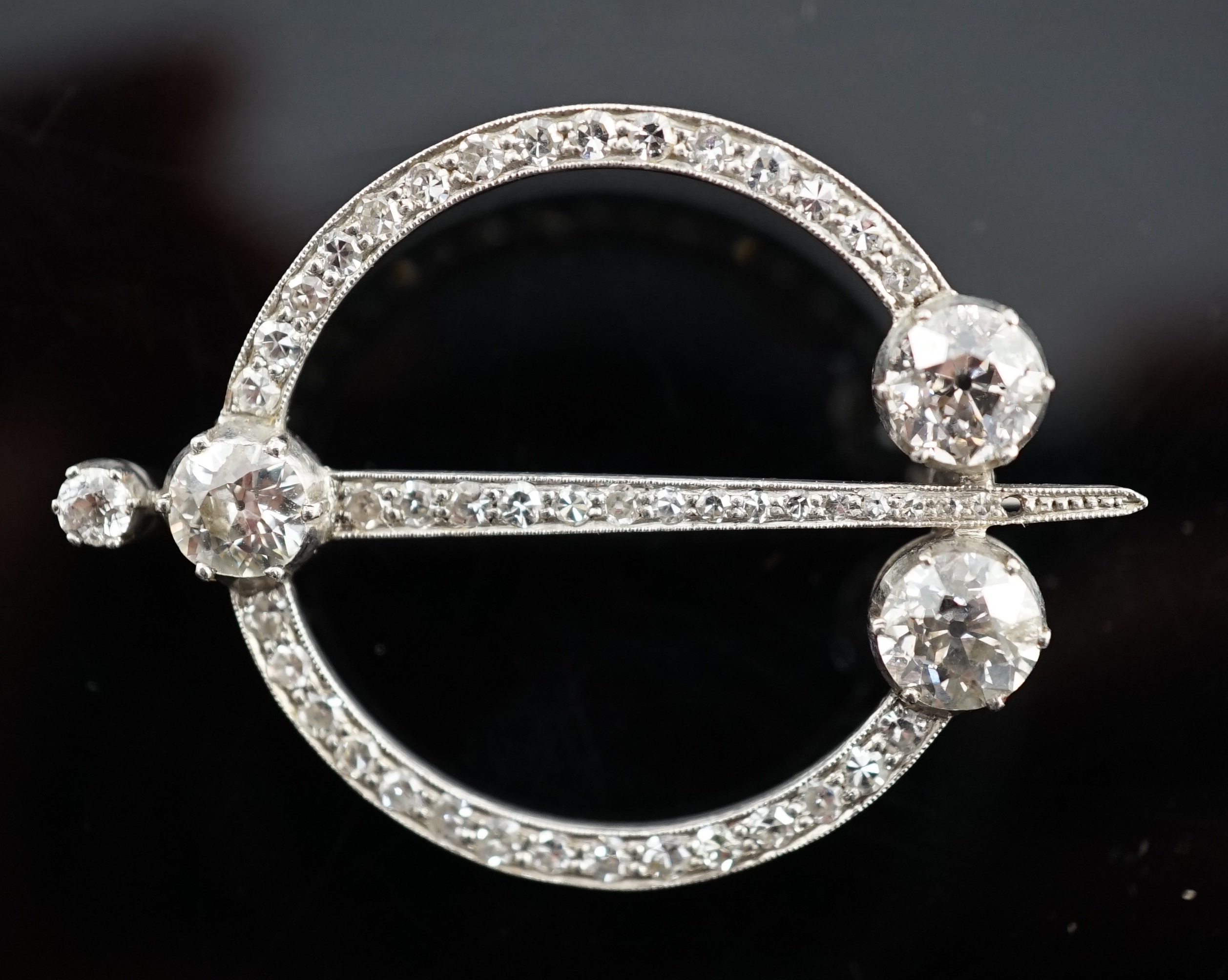 A 1920's platinum or white gold, diamond cluster set openwork 'dagger and circle' brooch